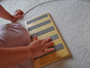 Imagen de un bebé jugando con las tablillas de tacto. Usando la tablilla con las lijas degradadas.